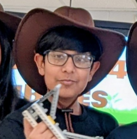 arsh in a brown cowboy hat and glasses, holding a robotics frame